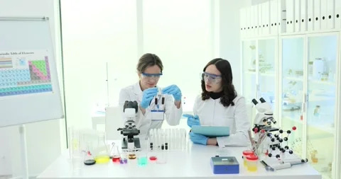 Women scientist couple study samples and write data in laboratory Stock Footage 318299808