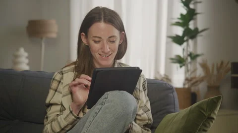 Women Scrolling Tablet While Sitting on Couch Stock Footage 278681429