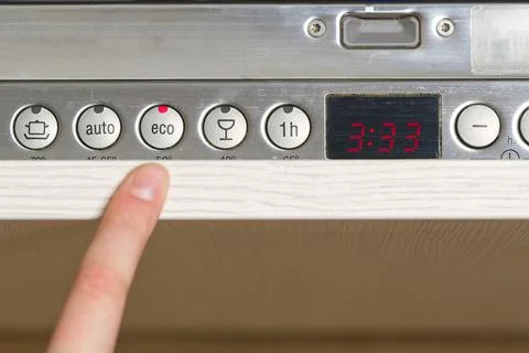 Women sets up a eco program on the panel of dishwasher, to save water and Foto stock