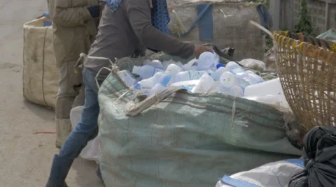 Women sort through a large bag of empty white plastic water bottles Stock Footage 61042025