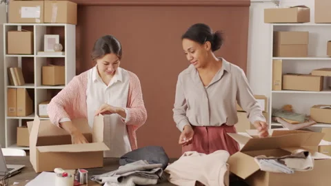 Women Sorting through Clothes and Packing Orders Stock Footage 142994269