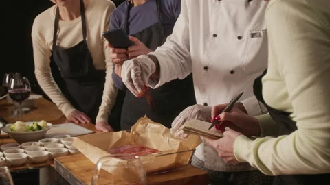 Women Taking Notes on How Professional Chef Seasoning Meat During Master class Stock Footage 332572738