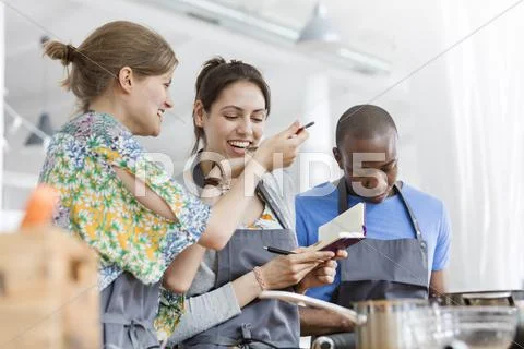 Women tasting food in cooking class kitchen Stock Photos
