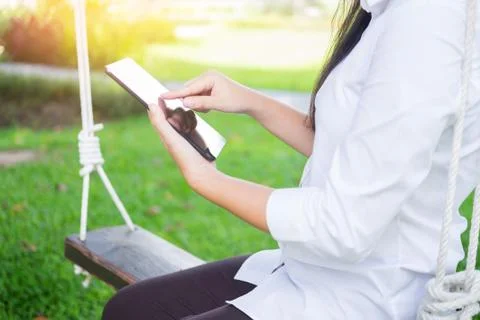 Women uses tablet for working while lying on a sunbed in garden. Stock Photos