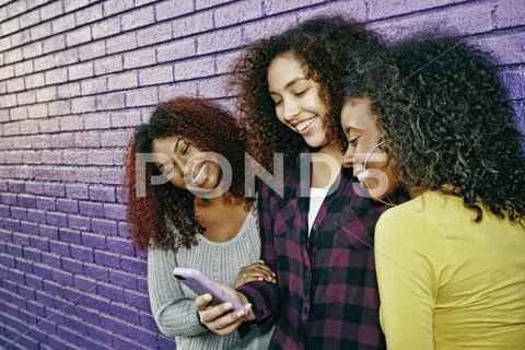 Women Using Cell Phone Outdoors At Purple Wall