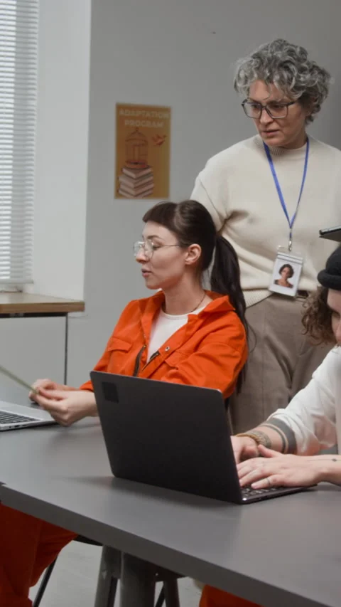 Women Using Computers with Teacher Assisting in Correctional Facility Vertical Stock Footage 329011320