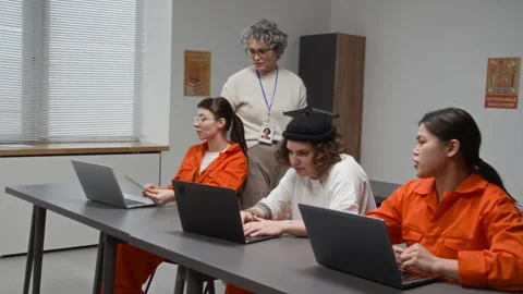 Women Using Laptops with Teacher Assisting during Computer Class in Prison Stock Footage 328997769