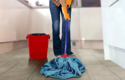 Women using a mop to clean the kitchen floor Stock Photos