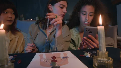 Women Using Pendulum, Poster, Crystals, Candles and Phone at Prediction Session Stock Footage 299190701