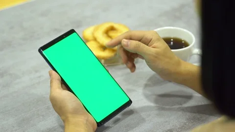 Women using smart phone slide finger green screen with cup of coffee and snacks Stock Footage 113045247