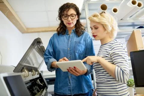 Women using tablet near plotter Fotos de archivo
