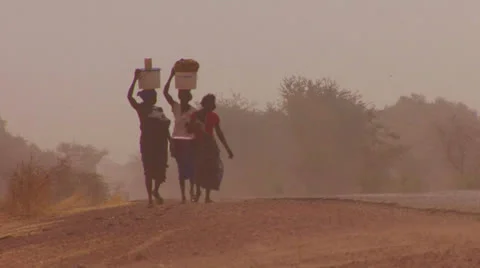 Women walk carrying goods on their heads through the Sahara desert in mali. Stock Footage
