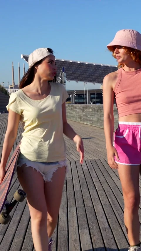 Women walking and roller skating on wooden pier Stock Footage 309984653