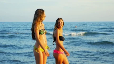 Women walking on the beach at sunset slow motion medium shot Stock Footage