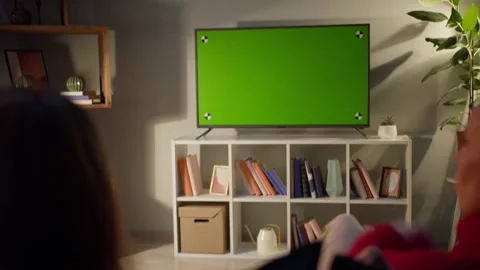 Women watching television with chroma green screen. Girlfriends switching Stock Footage