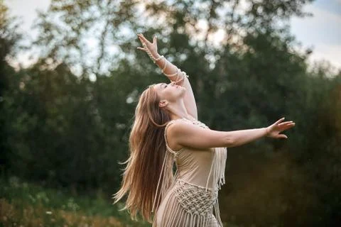 Women without makeup dancing in a field with flowers in a beige dress. Stock Photos