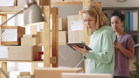 Women Working on Tablets and Checking Parcels in Shop Storage Stock Footage 146827525