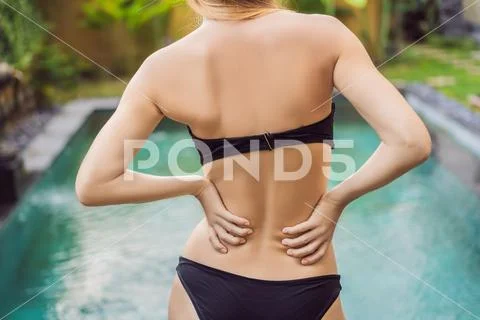 Women's back hurts against the backdrop of the pool. Pool helps with back pain Stock Photos