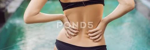 Women's back hurts against the backdrop of the pool. Pool helps with back pain Stock Photos