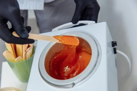 Womens DIY. Step 4/8 Wait for the wax to warm up and scoop it up with a spatula. Stock Photos