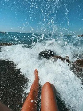 Women's feet in sea water and spray Stock Photos