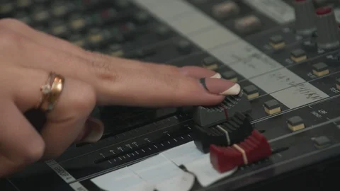 Women's finger touching volume level sliders on mixing console, close up Vidéo 102959748