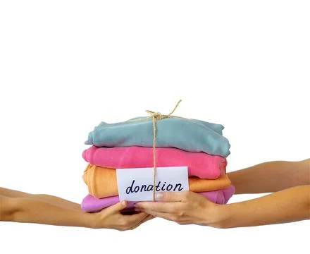 Women's hand give a stack of clothes to children's hands. Helping the poor Stock Photos
