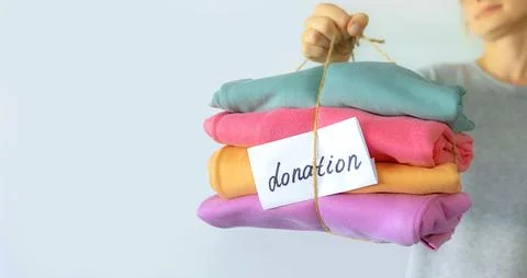 Women's hand give a stack of clothes to children's hands. Helping the poor Stock Photos