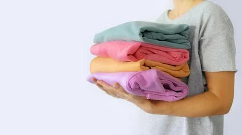 Women's hand give a stack of clothes to children's hands. Helping the poor Stock Photos