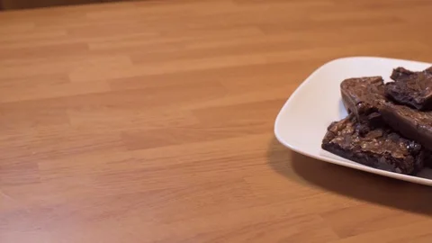 Womens hand grabbing a brownie off a stack of brownies on a white plate Stock Footage 121609459