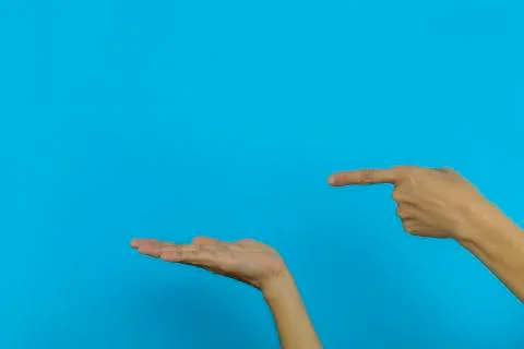 Women's hand Two hands One hand pointing the other hand Open hands on blue ba Stock Photos