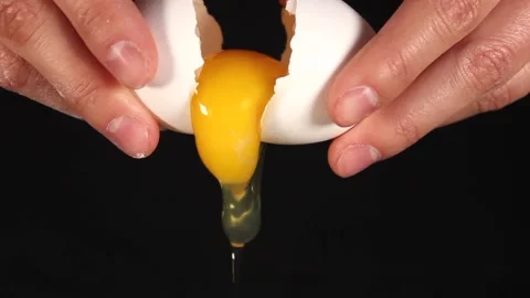 Women's hands are cracking white eggs. The yolk is poured out. Unrecognizable Stock Footage 218976078