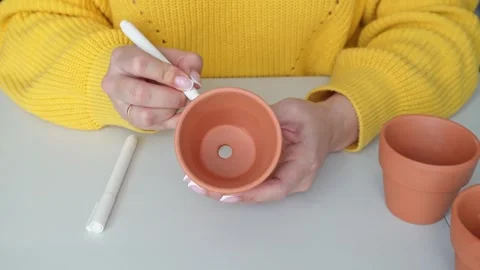 Women's hands are drawn with a white marker on a small clay pot Stock Footage 306643305