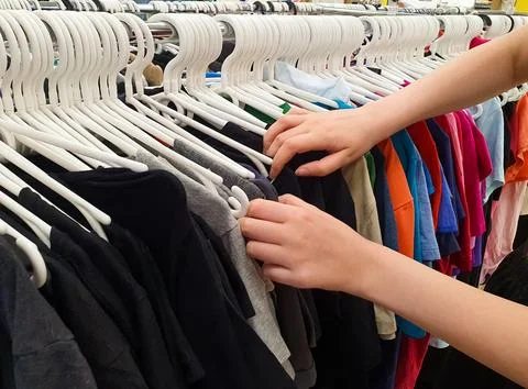 Women's hands are sorting through clothes on hangers Stock Photos