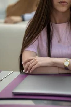 Women's hands are on the table in front of a closed laptop Stock Photos