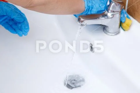 Women's hands in blue gloves clean the sink Stock Photos