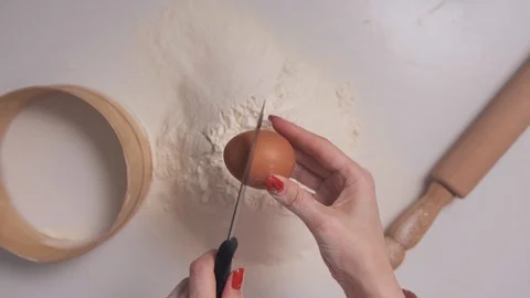 Women's hands break an egg into flour for making dough, top view, POV. Vídeos de archivo 129267236