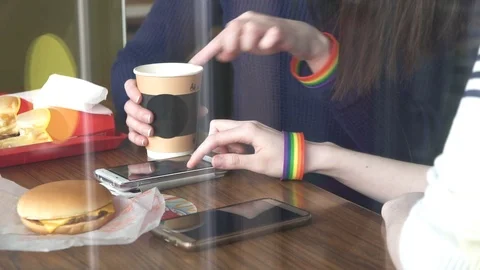 Women's hands in the cafe using a phone with LGBT bracelets close up Stock Footage 87595684