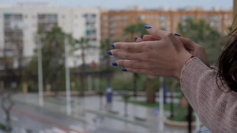 Women's hands clapping from their balcony on a cloudy day Stock Footage 128975075