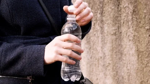 Women's hands close the lid of a plastic bottle with spring water Stock Footage 105464800