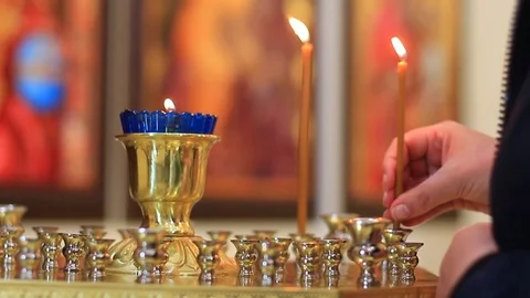 Women's hands close-up put a candle in the temple Stock Footage 107874823