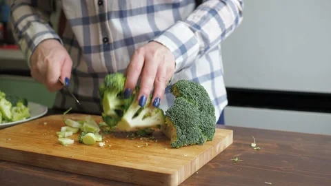 Women's hands cut broccoli on a cutting board with a knife. healthy eating Video stock 166111913