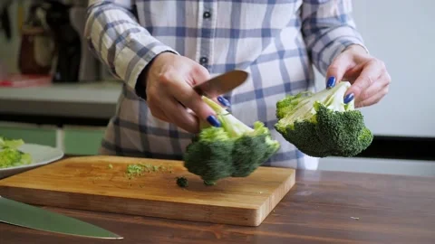 Women's hands cut broccoli on a cutting board with a knife. healthy eating Stock Footage 167608786