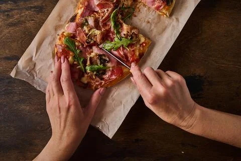 Women's hands cut with knife rectangular Roman pizza Stock Photos