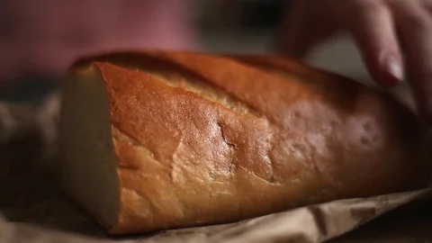 Women's hands cut a loaf of bread on paper Stock Footage 101920681