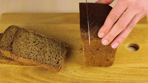 Womens hands cut loaf of bread on a cutting board with a knife. 스톡 동영상 150960736