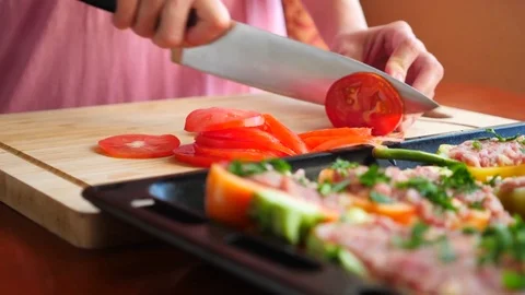 Women's hands, cut thin tomato slices into stuffed zucchini. close-up. 4k, slow Stock Footage 81050597