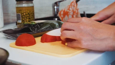 Women's hands cut tomatoes with a white ceramic knife Stock Footage 112043512