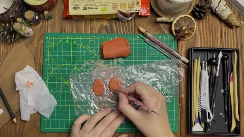 Women's hands draw face on clay with metallic stick. Stock Footage 161904076