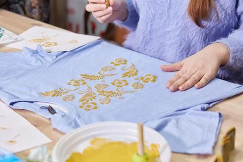 Women's hands fill the pattern on the fabric with paint. Stock Photos